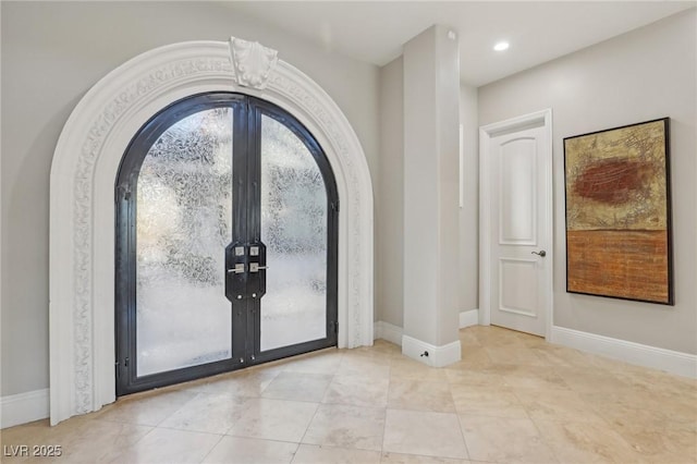 tiled entrance foyer featuring arched walkways, recessed lighting, french doors, and baseboards