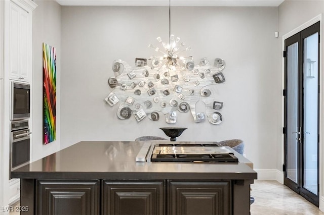 interior space featuring dark countertops, a center island, black microwave, stainless steel oven, and white cabinets