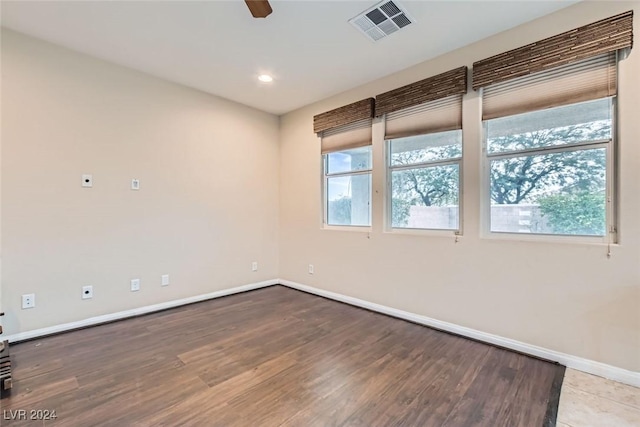 empty room with ceiling fan, a healthy amount of sunlight, and hardwood / wood-style flooring