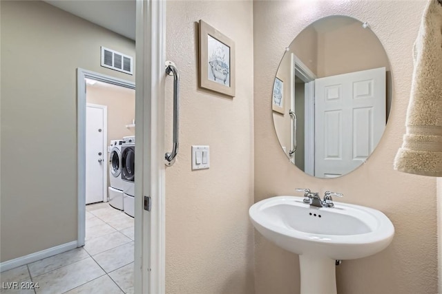 bathroom with washing machine and dryer, tile patterned flooring, and sink