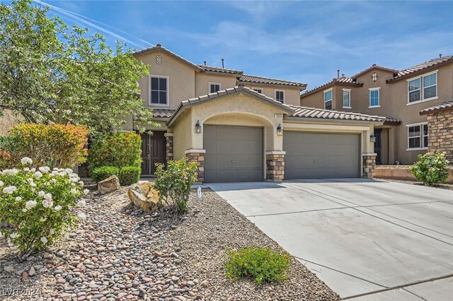 3605 Sapphire Sea Ct, North Las Vegas, NV 89031 - mediterranean / spanish house with a garage, a tiled roof, driveway, stone siding, and stucco siding