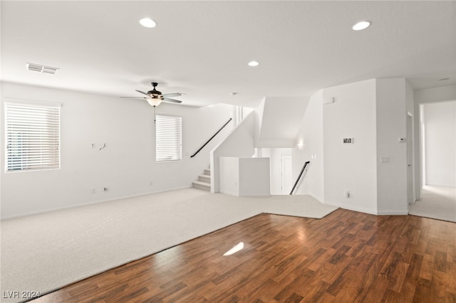 unfurnished living room with dark wood-type flooring, ceiling fan, and a healthy amount of sunlight