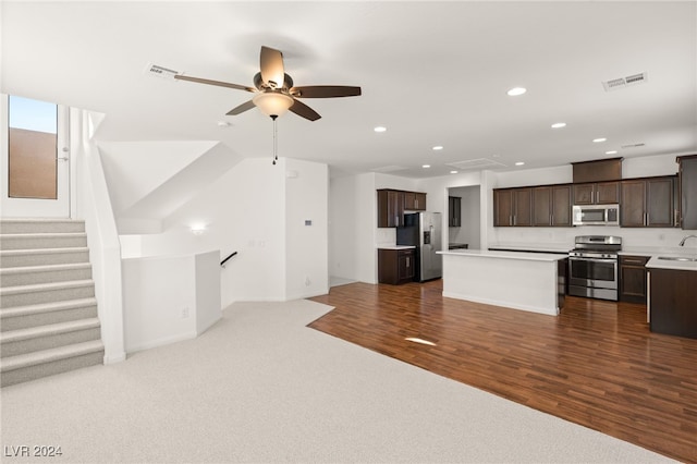 kitchen with dark brown cabinetry, sink, hardwood / wood-style floors, a kitchen island, and appliances with stainless steel finishes