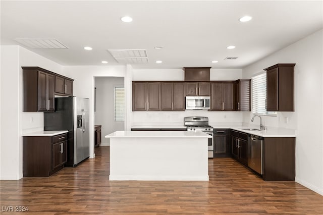 kitchen featuring appliances with stainless steel finishes, a kitchen island, dark wood-type flooring, and sink