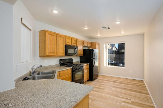 kitchen featuring black appliances, light wood-type flooring, and sink