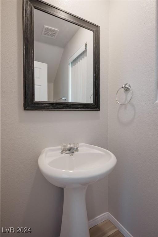 bathroom with hardwood / wood-style floors and vaulted ceiling