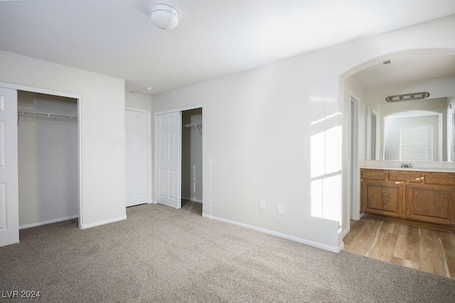 unfurnished bedroom with multiple closets and light carpet