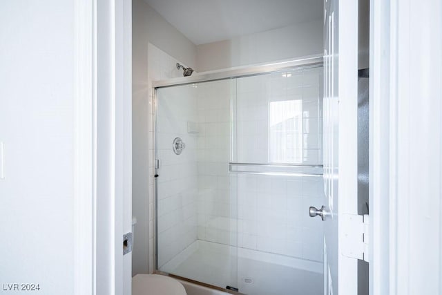 bathroom with a shower with door and toilet