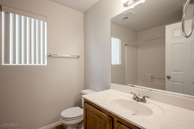 bathroom featuring a shower, vanity, and toilet