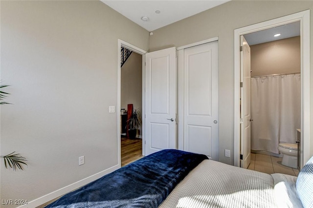 tiled bedroom with connected bathroom and a closet