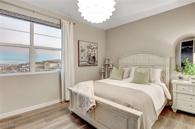 bedroom featuring light wood-type flooring and an inviting chandelier