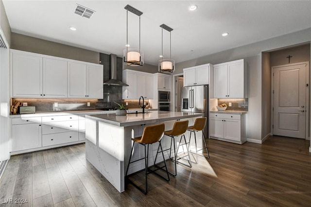 kitchen featuring a center island with sink, white cabinets, dark wood-type flooring, and wall chimney range hood