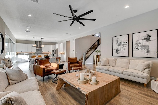 living room featuring ceiling fan, light wood-type flooring, and sink