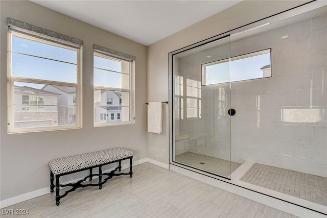 bathroom with a tile shower and a healthy amount of sunlight