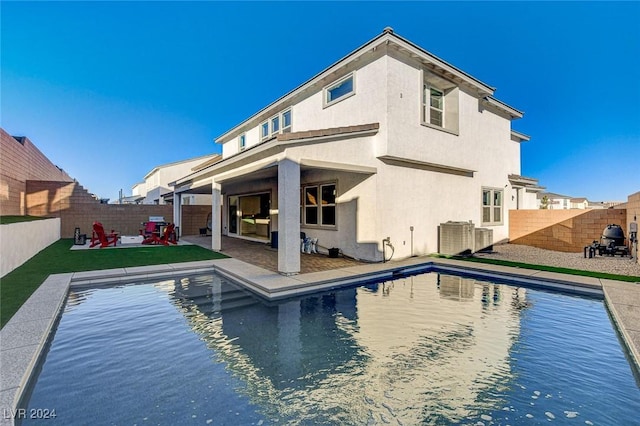 rear view of house featuring a fenced in pool and a patio area