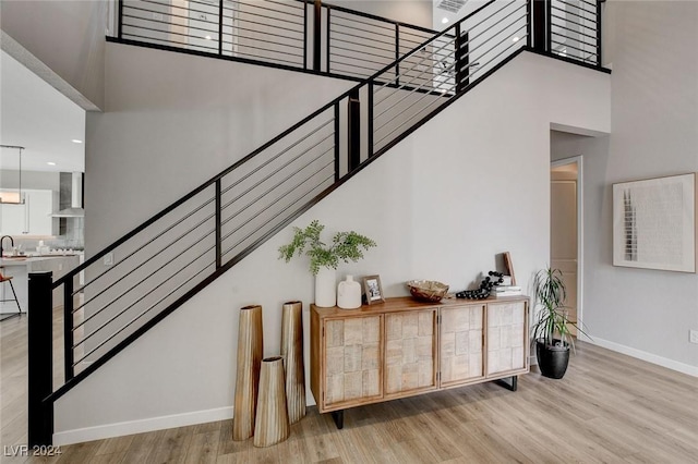 stairway with wood-type flooring and a high ceiling