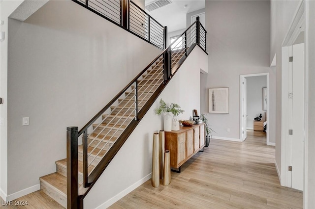 staircase featuring hardwood / wood-style flooring and a high ceiling