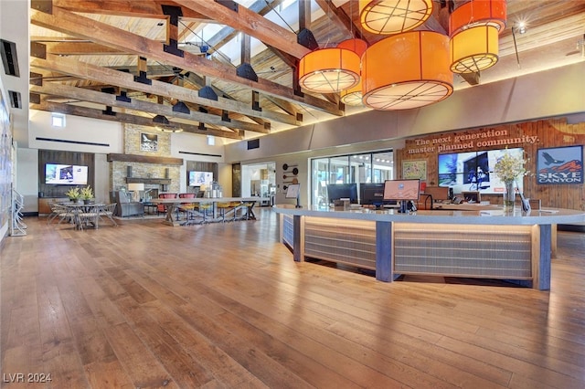 interior space with a fireplace, beamed ceiling, high vaulted ceiling, and wood-type flooring