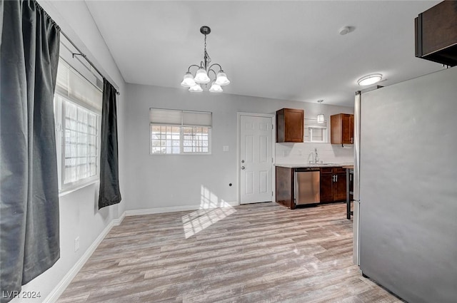 kitchen featuring appliances with stainless steel finishes, tasteful backsplash, sink, a chandelier, and hanging light fixtures