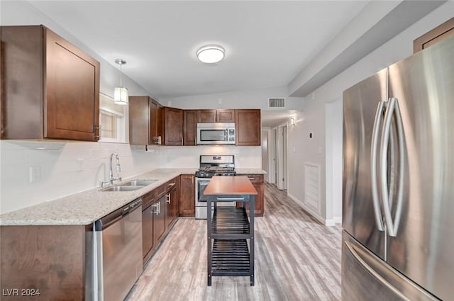 kitchen featuring sink, stainless steel appliances, light stone counters, vaulted ceiling, and decorative light fixtures