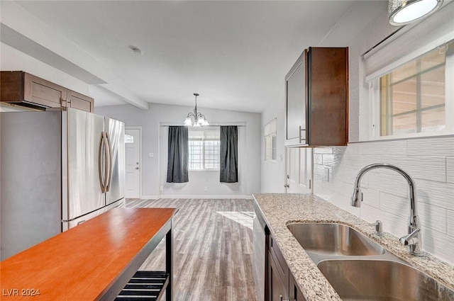 kitchen featuring an inviting chandelier, sink, vaulted ceiling with beams, appliances with stainless steel finishes, and light stone counters