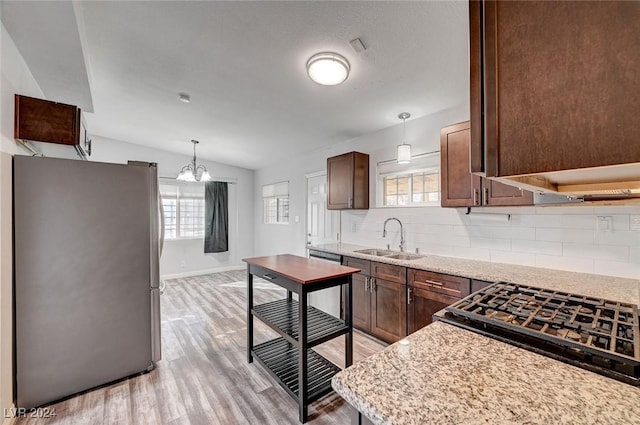 kitchen featuring pendant lighting, sink, appliances with stainless steel finishes, and vaulted ceiling