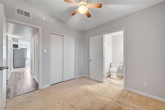 unfurnished bedroom featuring stainless steel refrigerator, ceiling fan, a closet, and light colored carpet