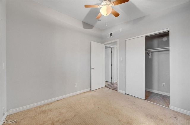 unfurnished bedroom featuring a closet, light colored carpet, and ceiling fan