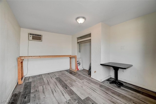 unfurnished bedroom featuring an AC wall unit, a closet, and wood-type flooring