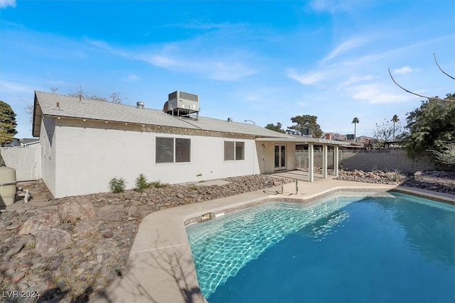 back of property featuring cooling unit, a fenced in pool, and a patio area