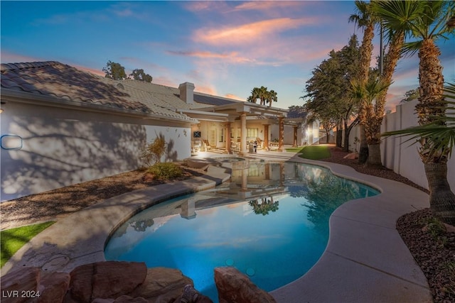 pool at dusk with a patio area