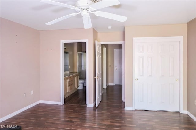 unfurnished bedroom featuring a closet, ensuite bath, ceiling fan, and dark wood-type flooring