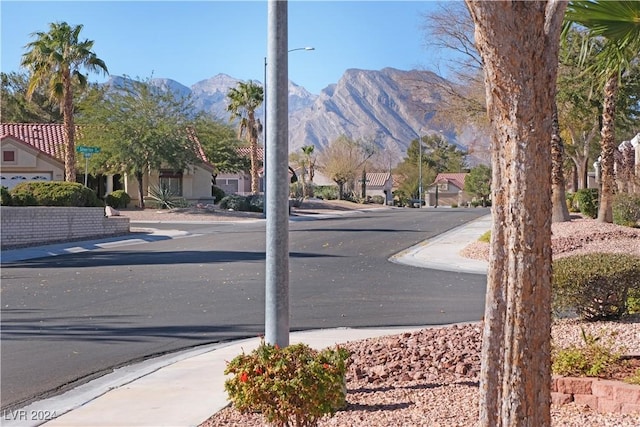 view of road featuring curbs, street lighting, a residential view, sidewalks, and a mountain view