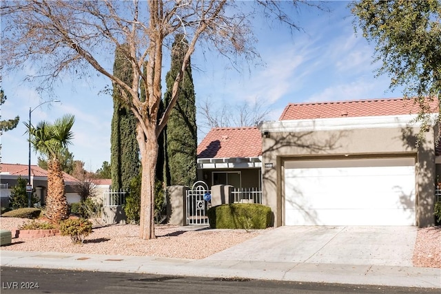 mediterranean / spanish-style home featuring driveway, a tiled roof, stucco siding, and an attached garage