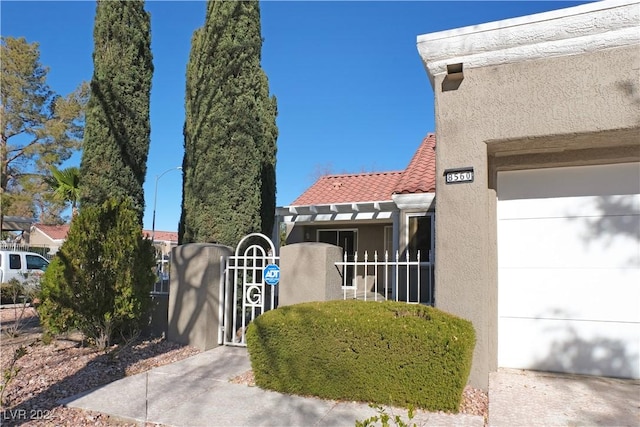 view of property exterior featuring a gate, fence private yard, stucco siding, and a tile roof