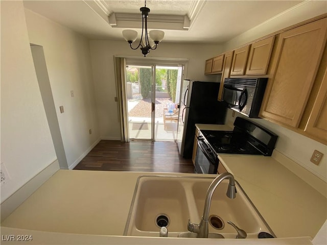 kitchen with a sink, a tray ceiling, dark wood-style floors, black appliances, and ornamental molding