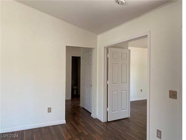 spare room featuring baseboards, vaulted ceiling, and dark wood-type flooring