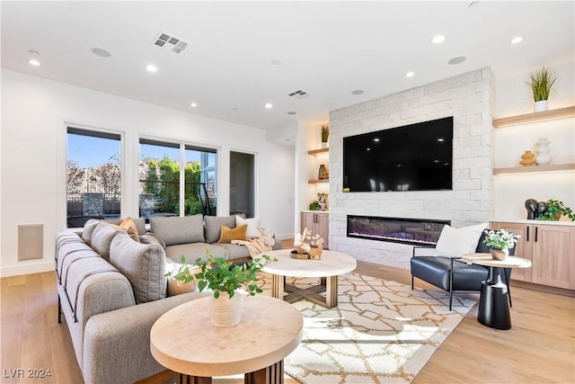 living room with a stone fireplace and light hardwood / wood-style flooring