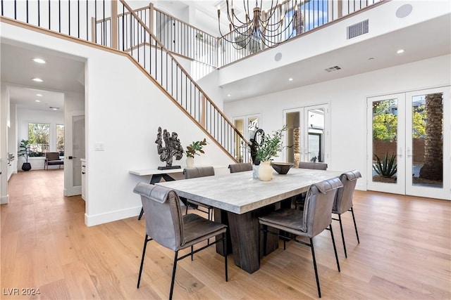 dining room with light hardwood / wood-style flooring, a high ceiling, and a notable chandelier