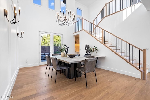 dining space featuring a high ceiling, light wood-type flooring, and a notable chandelier