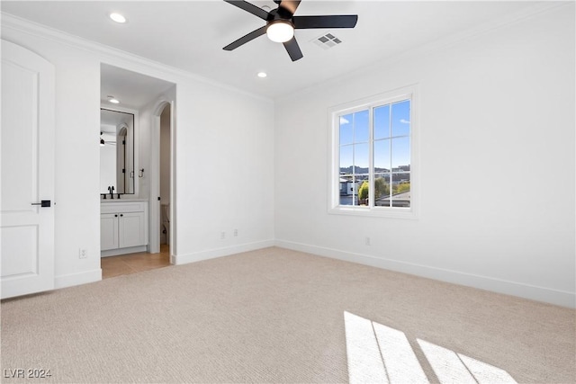 unfurnished bedroom with ensuite bathroom, crown molding, ceiling fan, and light colored carpet