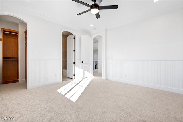 unfurnished bedroom with light carpet, ensuite bathroom, ceiling fan, a spacious closet, and a closet