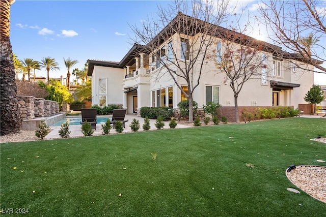 rear view of property featuring a yard, a balcony, and a patio