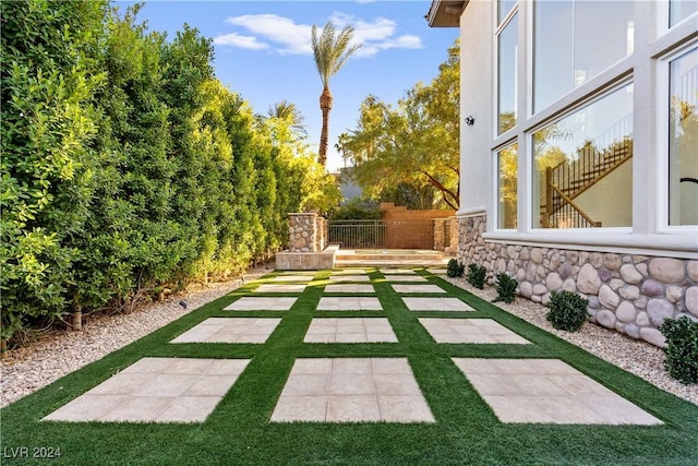 view of yard featuring an outdoor stone fireplace and a patio area