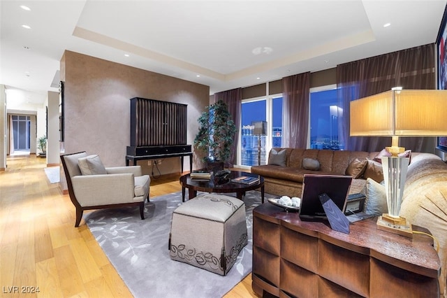 living room with a tray ceiling and light hardwood / wood-style flooring