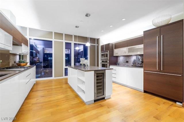 kitchen featuring a center island, beverage cooler, light hardwood / wood-style flooring, built in appliances, and decorative light fixtures