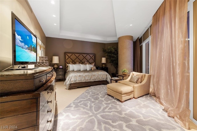 bedroom featuring light carpet and a tray ceiling