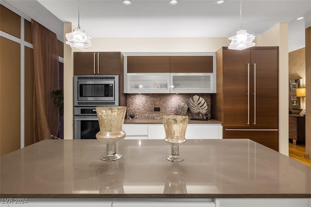 kitchen with white cabinetry, a center island, stainless steel appliances, tasteful backsplash, and pendant lighting