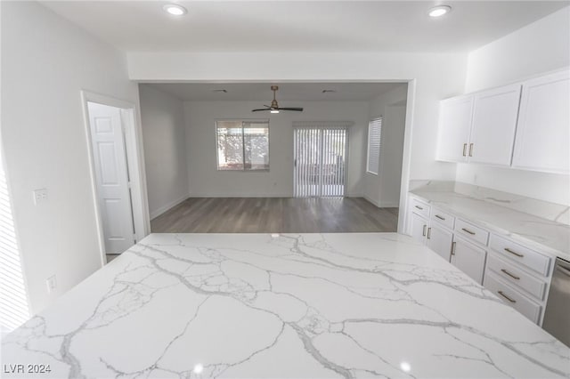 kitchen featuring ceiling fan, white cabinets, wood-type flooring, and light stone counters