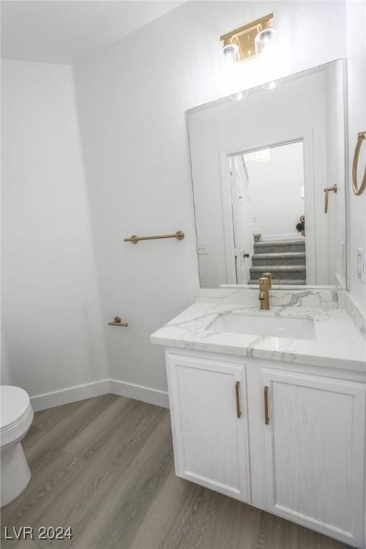 bathroom with hardwood / wood-style flooring, vanity, and toilet